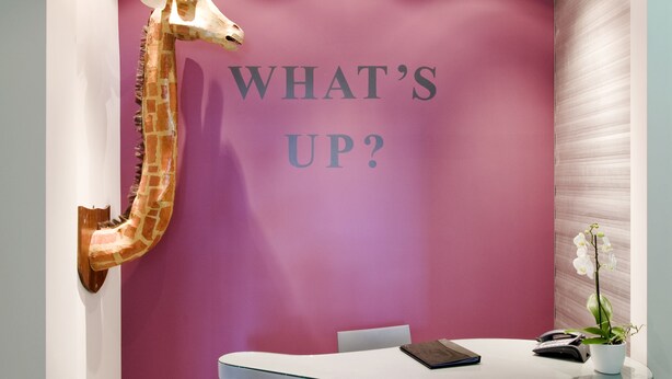 A reception desk with a giraffe head sculpture, a purple wall, and a white floor. - Nevern Place by Supercity Aparthotels (London)