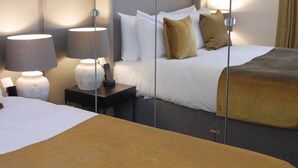 A hotel room with a large bed, bedside tables, a lamp, and framed pictures on the wall. - Nevern Place by Supercity Aparthotels (London)