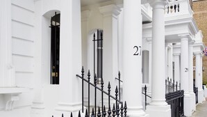 A row of white buildings with black iron railings and numbered columns. - Nevern Place by Supercity Aparthotels (London)