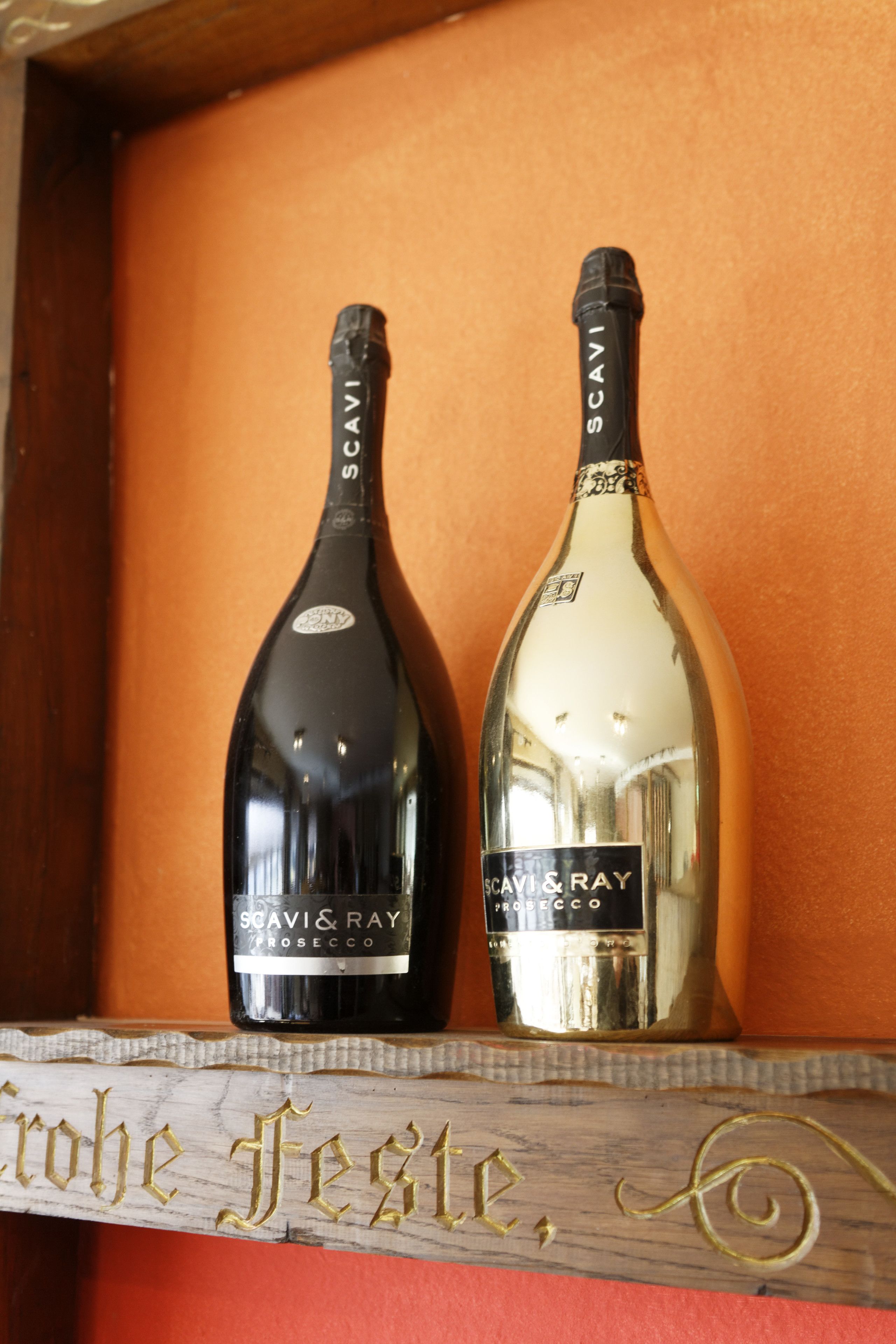 Dos botellas de vino prosecco Scavi & Ray sobre un estante de madera con un letrero que dice "Crohe Fest".