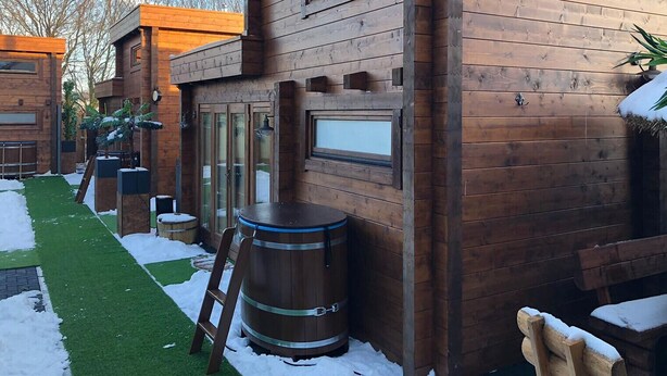 A wooden cabin with a large barrel, a ladder, and a bench. - Hotel Restaurant Rodizio Paderborn (Altenbeken)