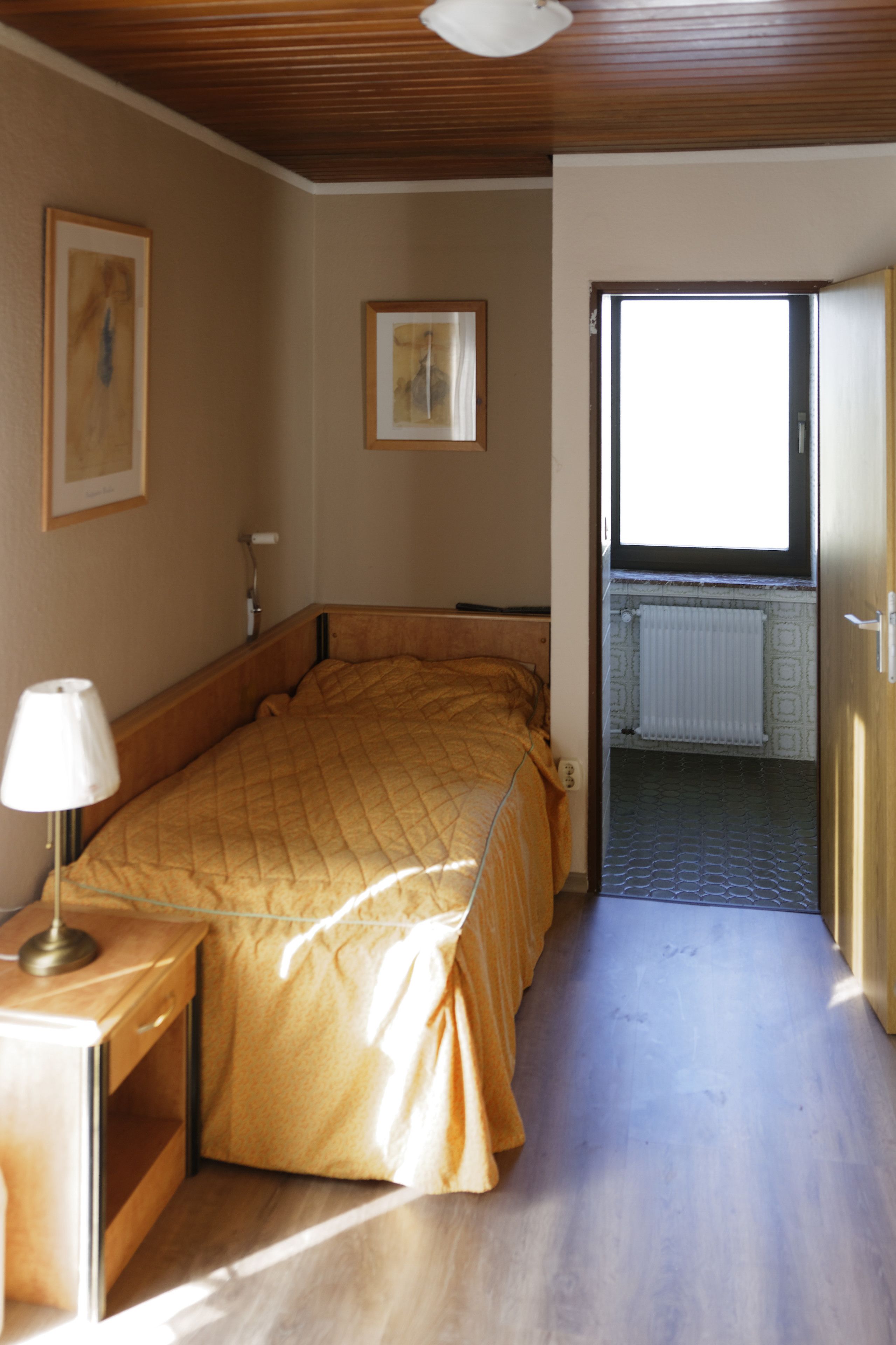 Ein Schlafzimmer mit einem Bett, einer Nachttischlampe und einem Fenster.