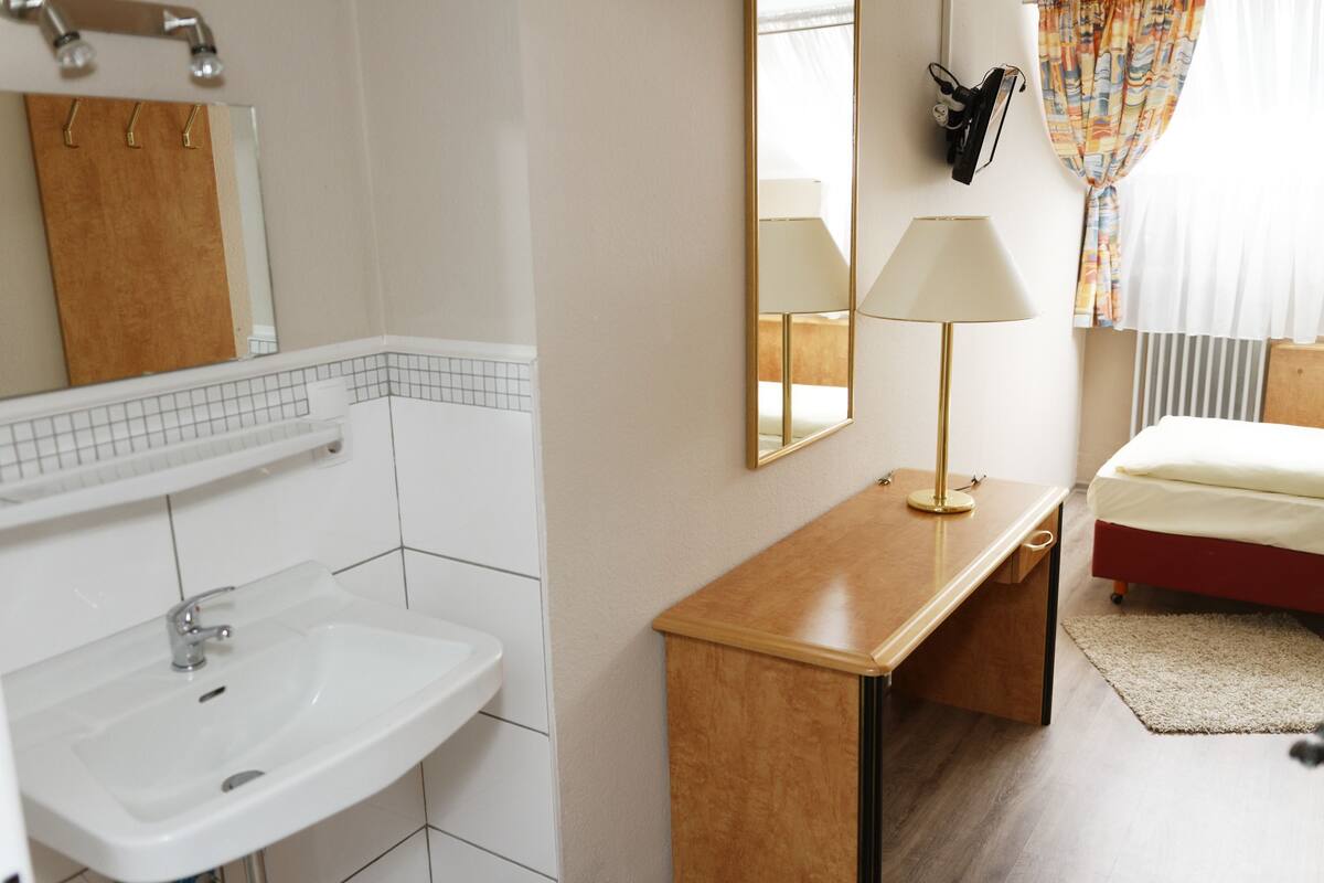 Une salle de bain avec un lavabo, un miroir et un porte-serviettes.