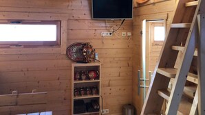 A wooden interior with a TV mounted on the wall, a shelf with decorative items, and a ladder. - Hotel Restaurant Rodizio Paderborn (Altenbeken)