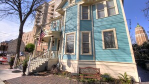 A multi-story building with a blue exterior, a front porch with a bench, and a staircase leading to the entrance. - Inn on the Riverwalk (San Antonio)