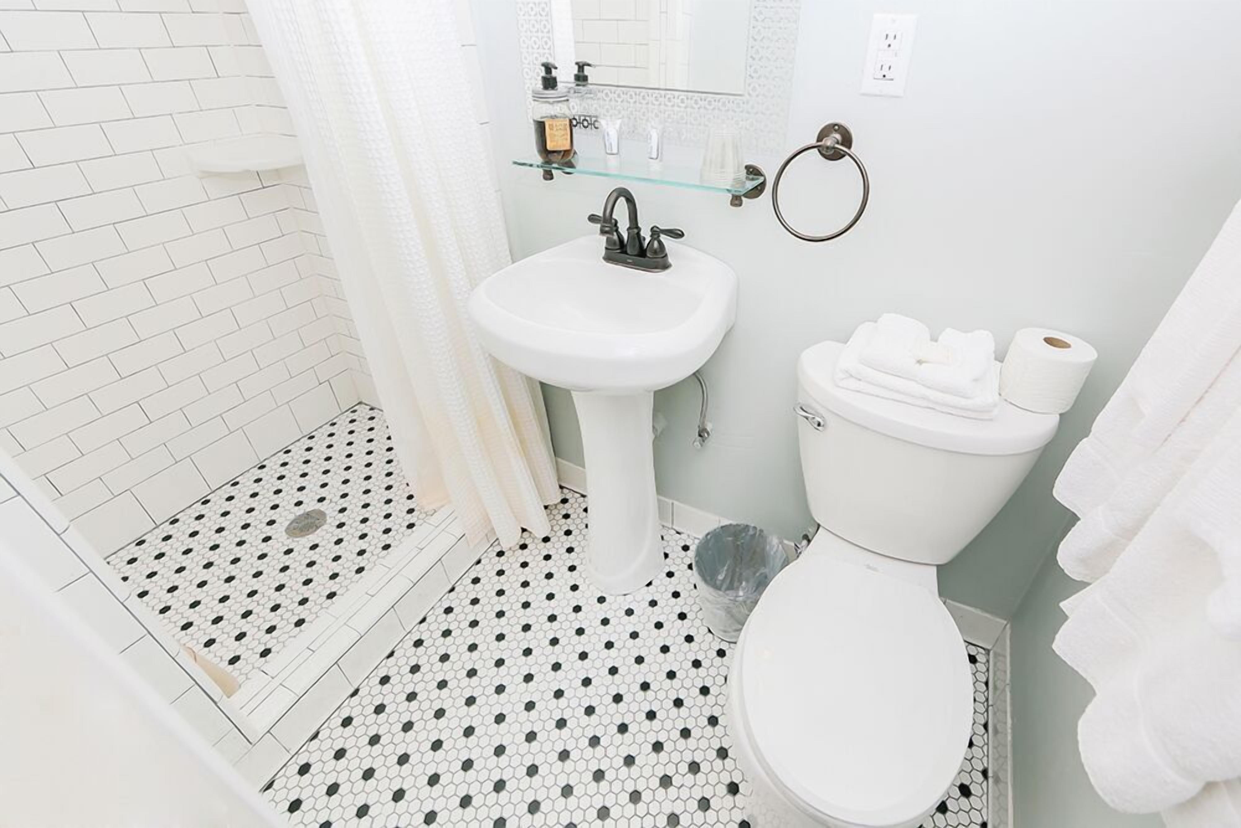 A bathroom with a white sink, toilet, and shower area.
