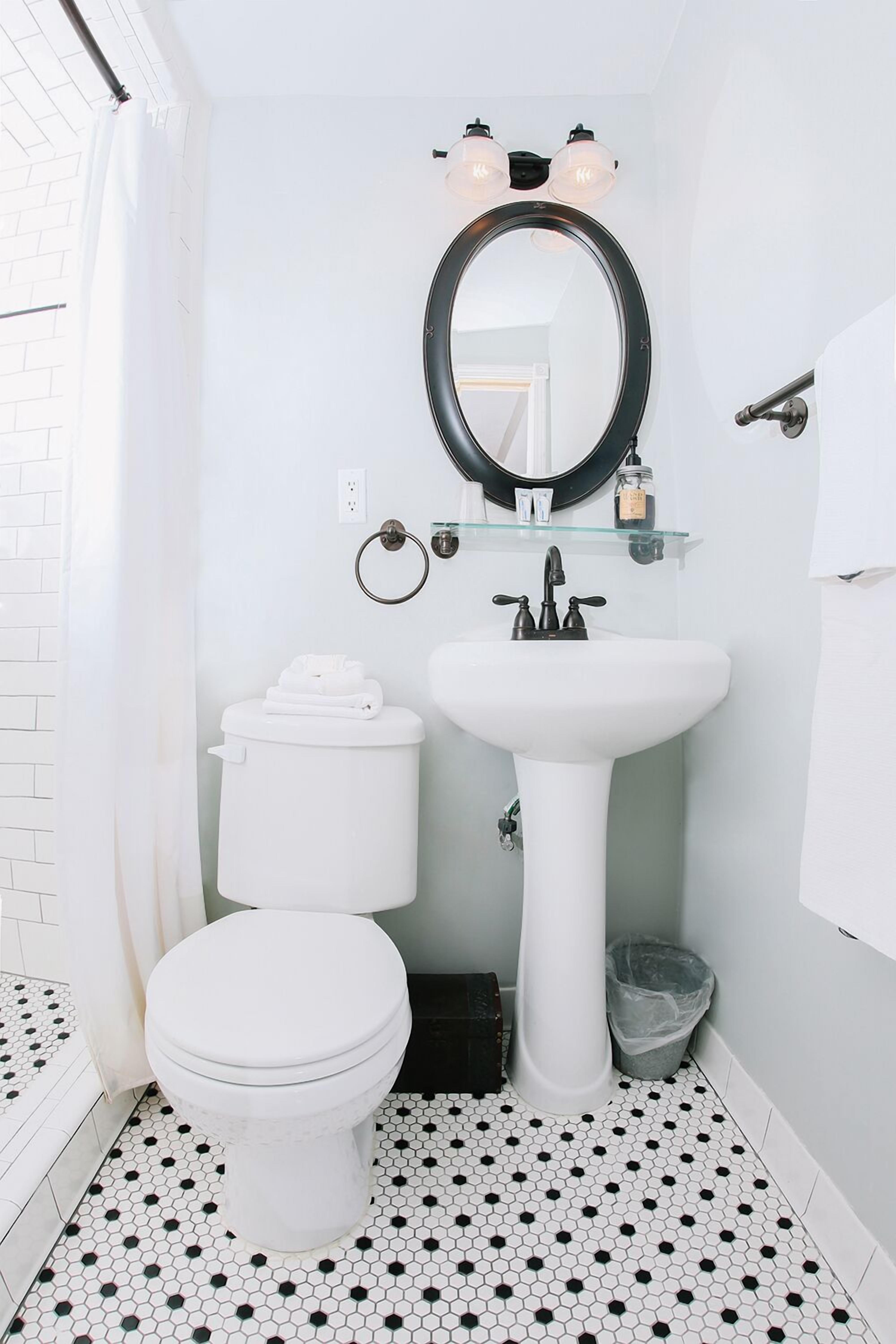 A bathroom with a toilet, sink, and mirror.