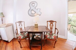 A dining area with a wooden table and two chairs with floral upholstery, a wall-mounted decorative letter, and a lamp on the side. - Inn on the Riverwalk (San Antonio)