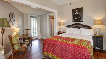 A bedroom with a large bed, a chair, a desk, and a nightstand.