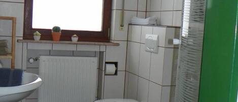 A small bathroom with a toilet, a sink, a window, and a radiator.