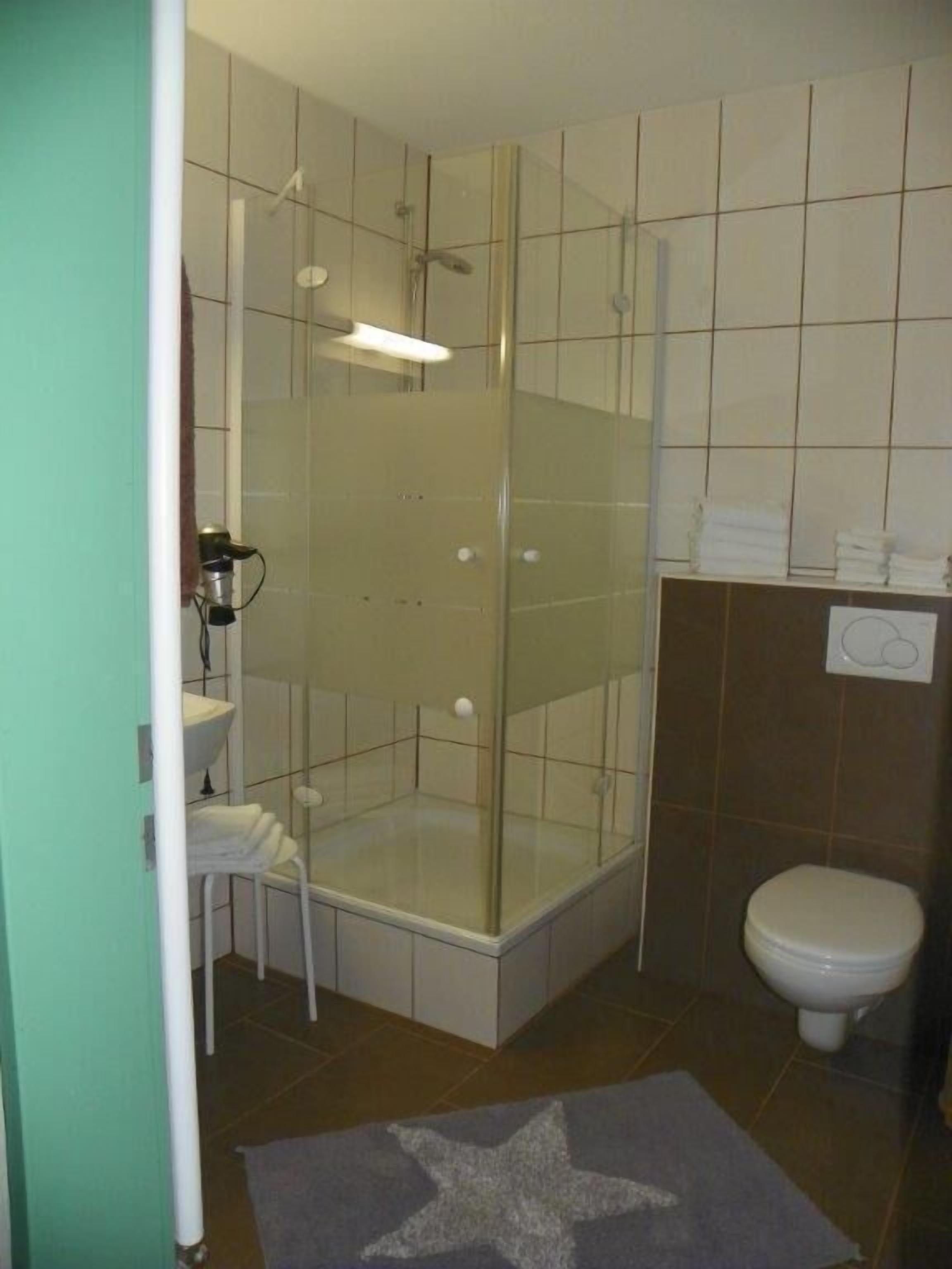 A bathroom with a glass-enclosed shower, a toilet, and a sink.