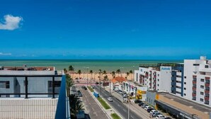 Un paisaje costero urbano con cielo azul despejado, una playa a lo lejos y edificios modernos a lo largo del paseo marítimo.