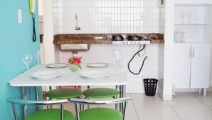 Una cocina con encimera blanca, sillas verdes y un lavabo.