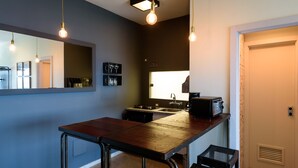 Uma cozinha moderna com parede azul escura, uma mesa de madeira e lâmpadas penduradas.
