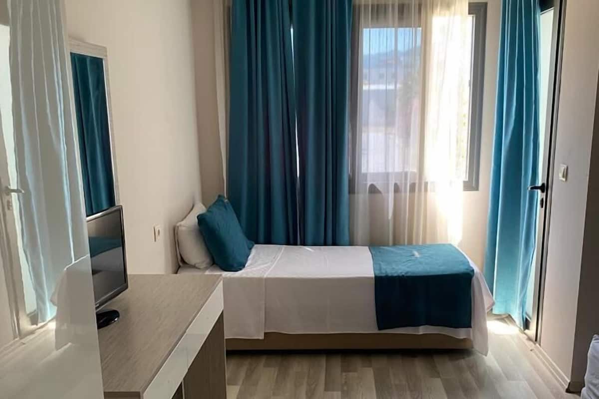 A compact room with a bed, a desk, and a television.