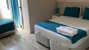 Una habitación de hotel con cama, mesita de noche y ventana con cortinas.
