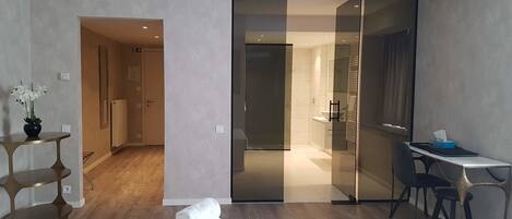 Una habitación de hotel moderna con una cama, un escritorio y una puerta corredera que da a un baño.