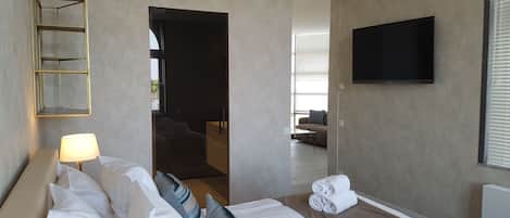 Habitación de hotel con cama, televisión, lámpara y vistas al exterior.