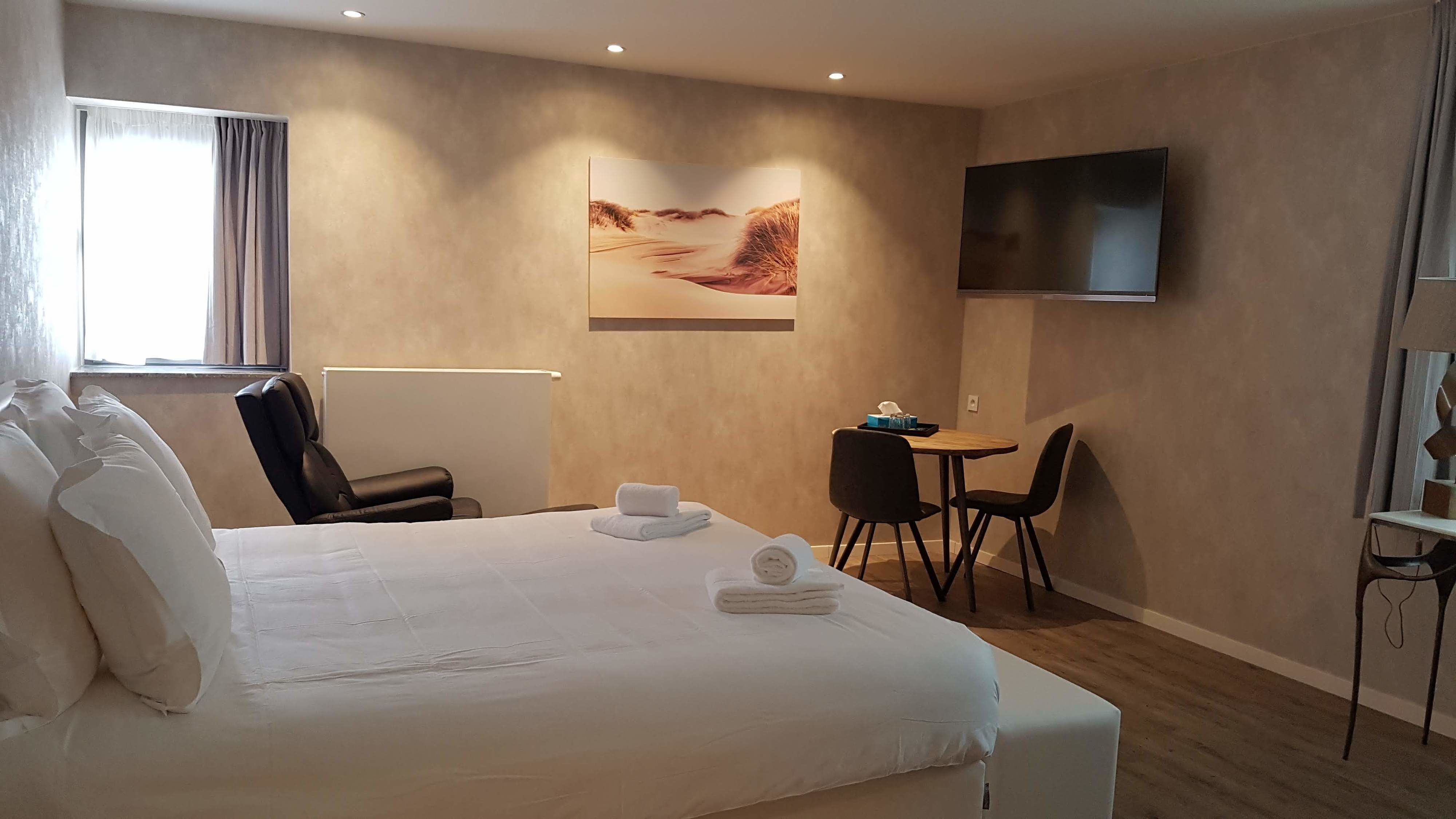 A hotel room with a large bed, a desk with a chair, a flat-screen TV, and a painting on the wall.