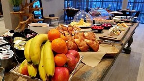 Un bufé con frutas, pasteles y diversos alimentos.