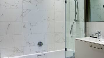 A modern bathroom with a glass-enclosed shower, a white bathtub, and a vanity with a mirror.