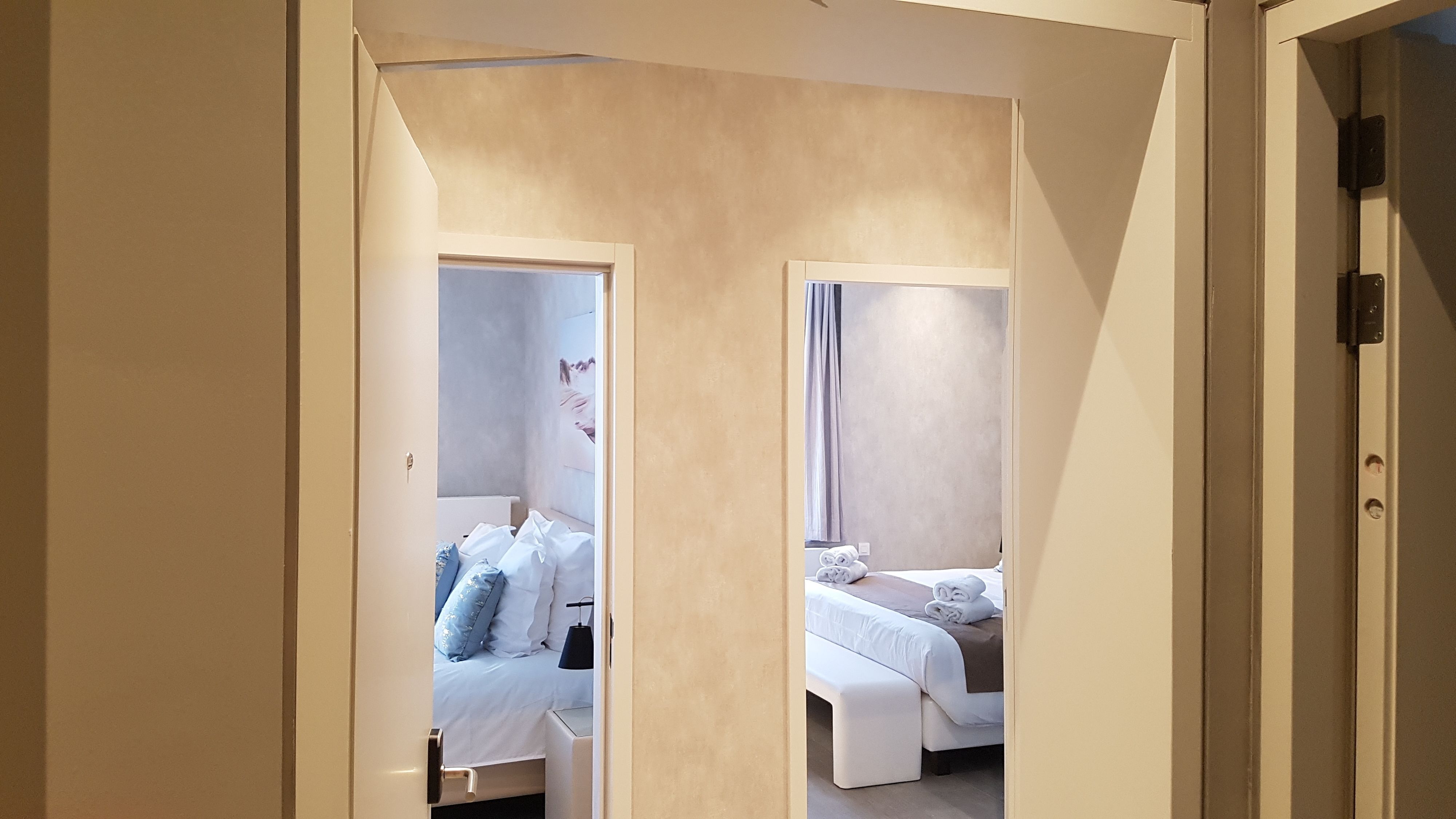 A hotel room with a bed, bedside table, and a mirror.