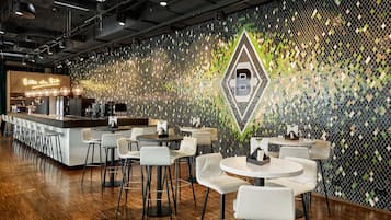 Eine moderne Bar mit Wandmuster, Barhocker und runden Tischen.