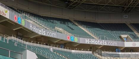 Un estadio con múltiples niveles de asientos, un anuncio destacado de H-Hotels.com y un cartel que indica la sección 19A.