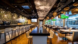 Un restaurante moderno con una barra larga, sillas blancas y una zona de bar con taburetes.