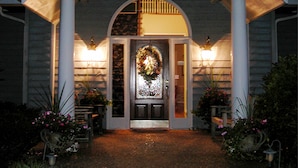 A house with a porch, a front door with a decorative glass panel, and two light fixtures on either side of the door. - Garden Inn Bed & Breakfast at Bee Rock (Monterey)