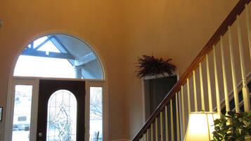 A spacious foyer with a chandelier, a staircase, and a door leading outside.