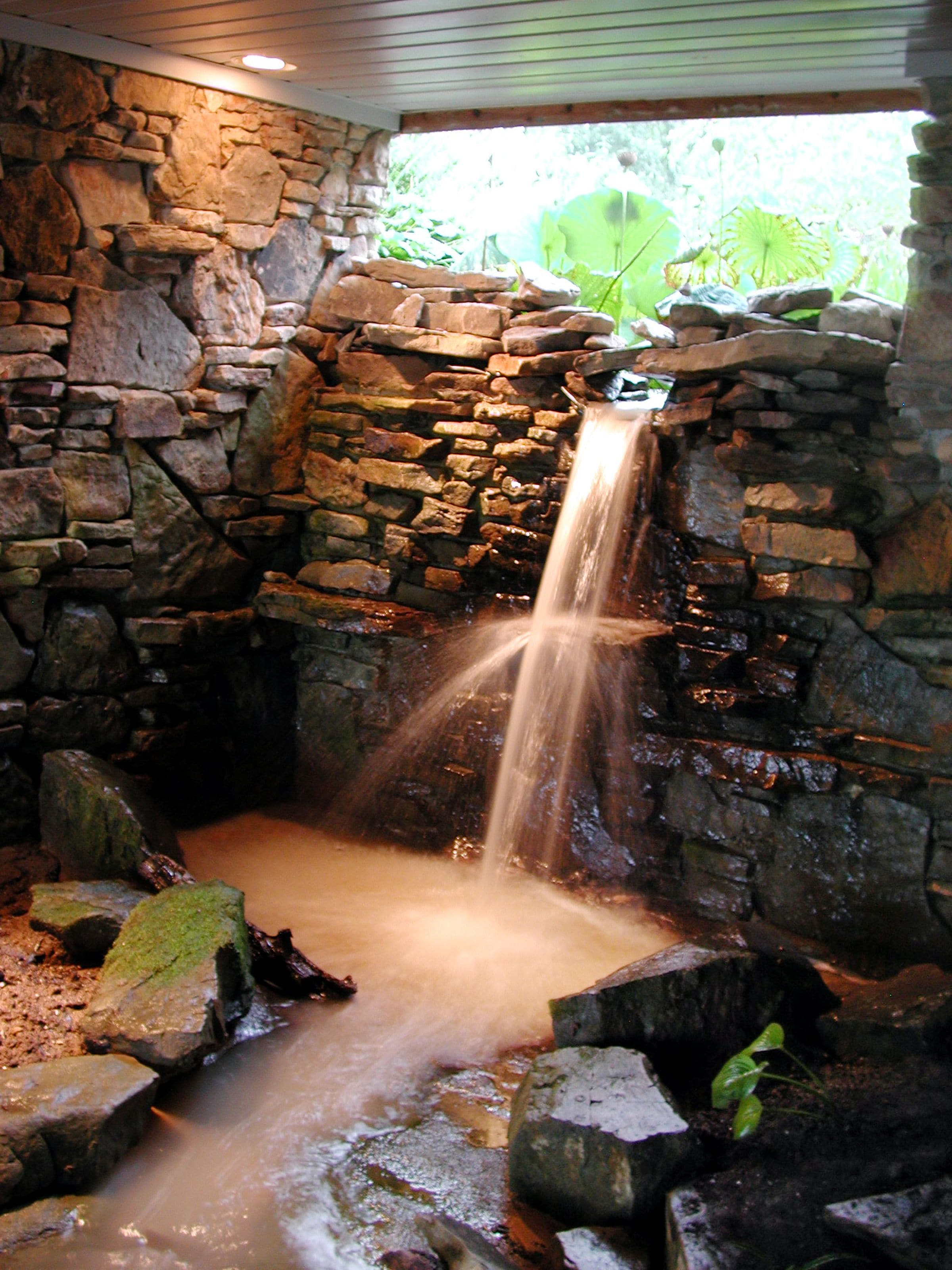 A stone waterfall feature with a naturalistic setting, including rocks and plants.
