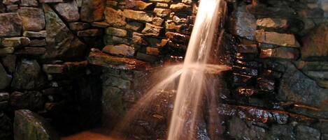 A stone waterfall feature with a naturalistic setting, including rocks and plants.