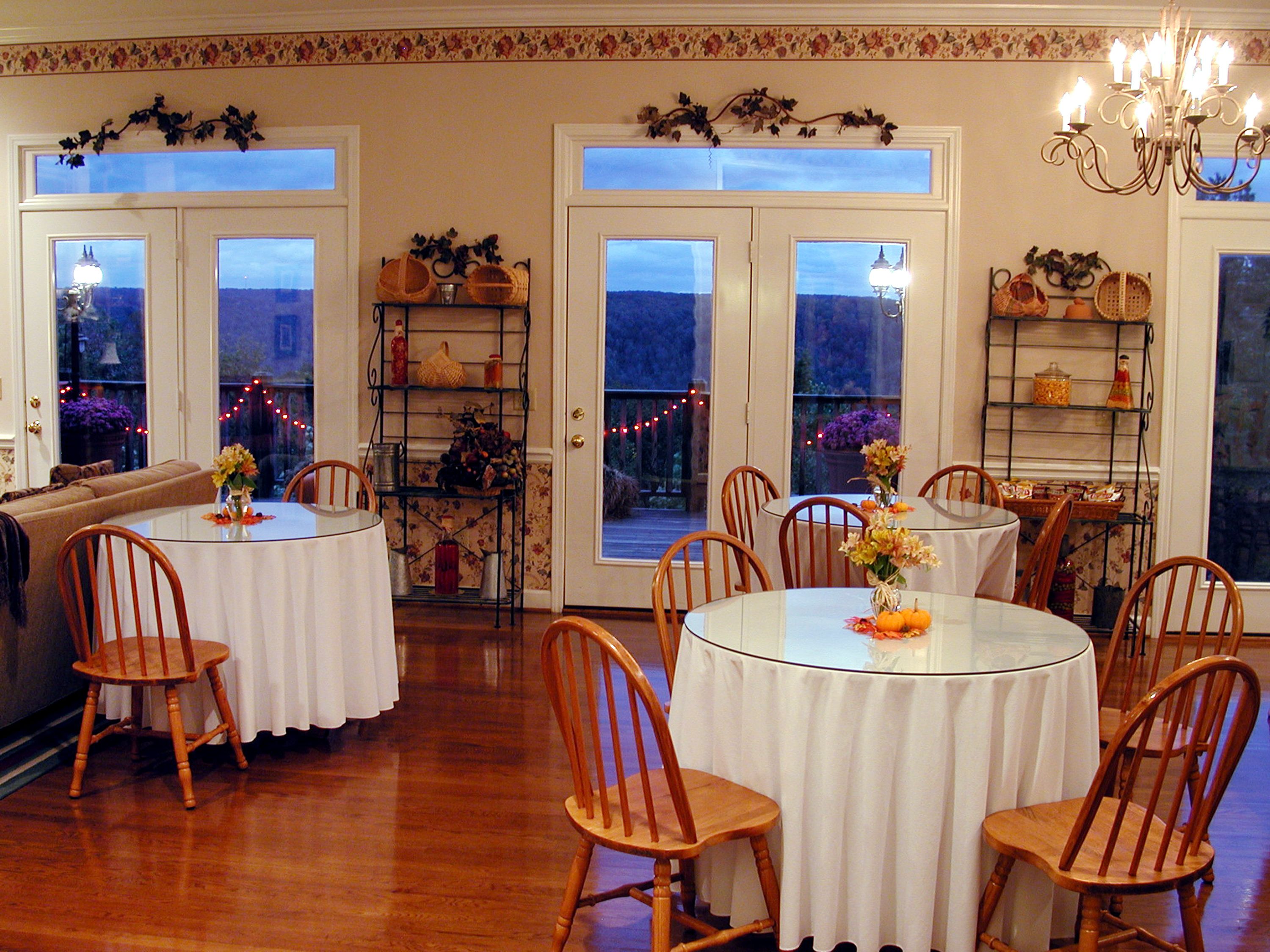 A dining area with round tables and wooden chairs, decorated with floral centerpieces.