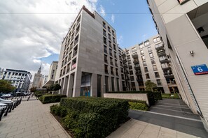 A modern multi-story building with a flat facade, several balconies, and a parking area with a sign indicating the entrance. - Apartament Nowy Świat by Your Freedom (Warsaw)