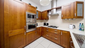 A modern kitchen with wooden cabinets, stainless steel appliances, and a white ceiling light.