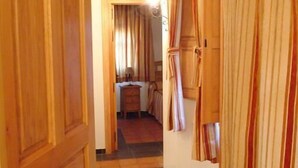 Un couloir avec des portes en bois, des rideaux à rayures et un sol carrelé.