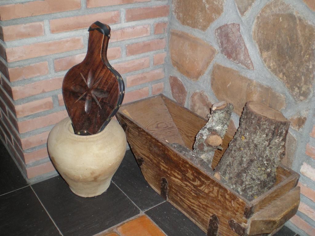Un rincón rústico con un cofre de madera y un florero de cerámica al pie de una pared de ladrillo.