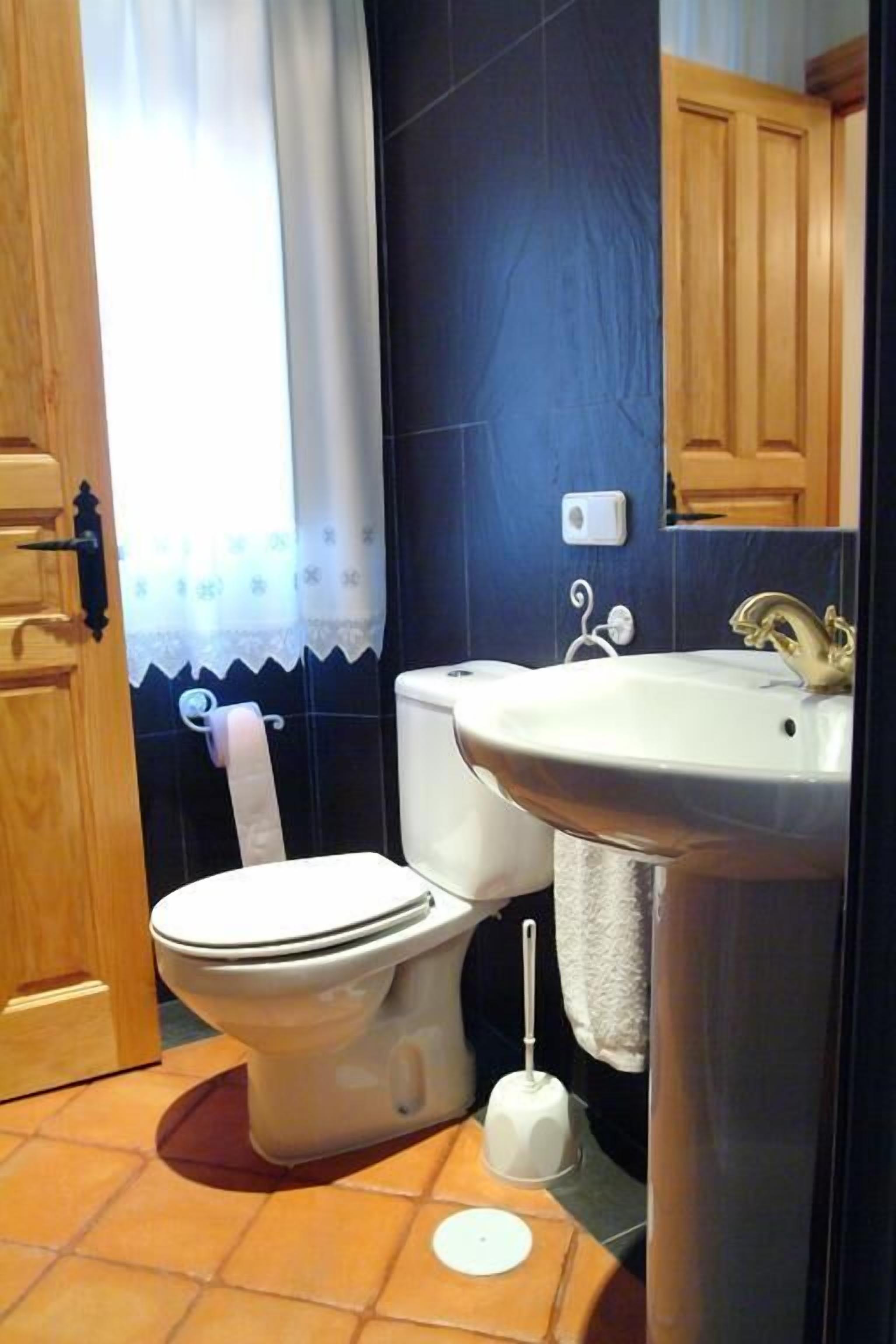 A bathroom with a toilet, sink, and shower curtain.
