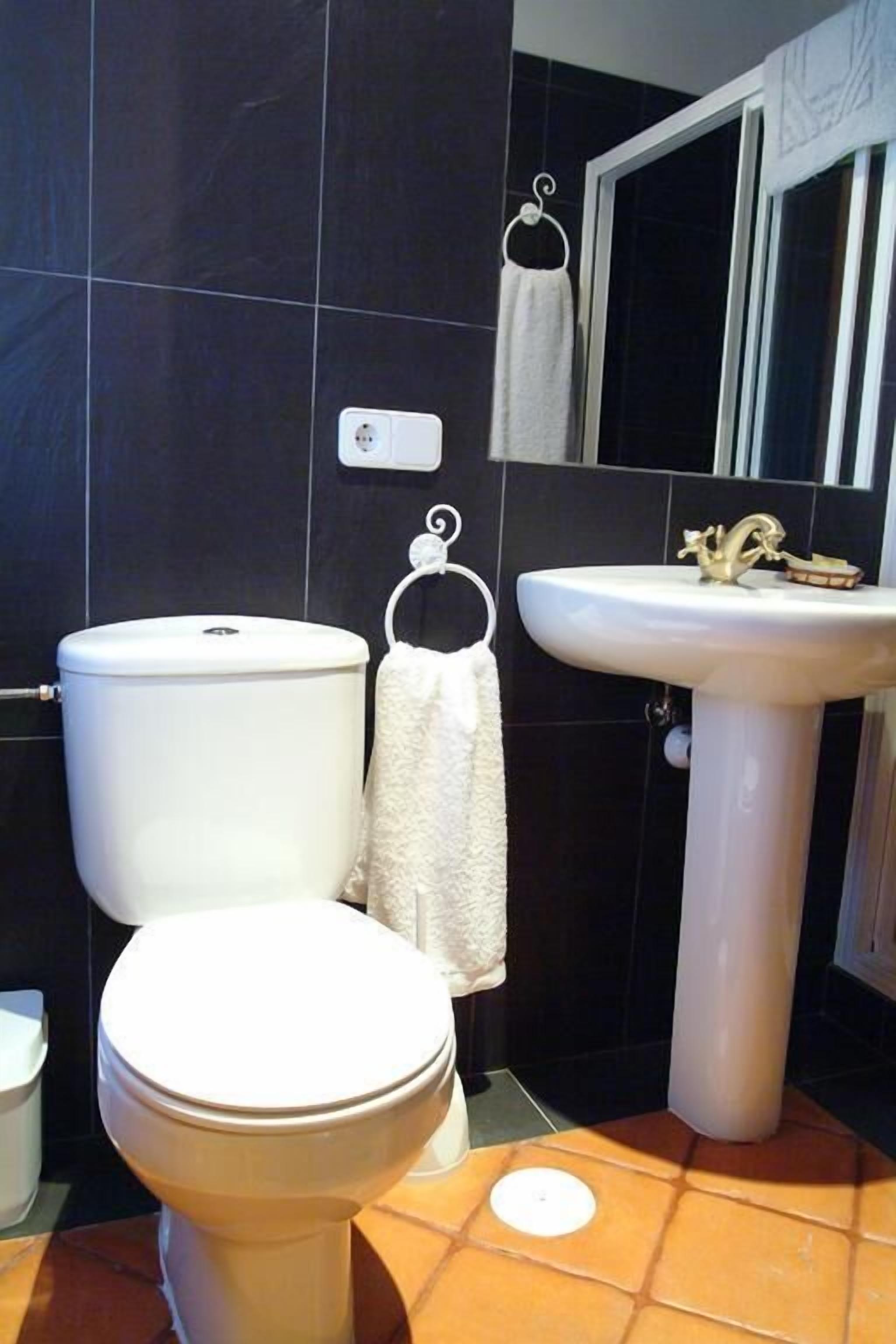 Une salle de bain équipée de toilettes, d’un lavabo et d’un porte-serviettes.
