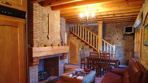 Un salon chaleureux avec une cheminée, des meubles en bois et un escalier menant à un autre niveau.