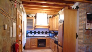 Une cuisine avec des meubles de rangement en bois, un four à micro-ondes et un extincteur.