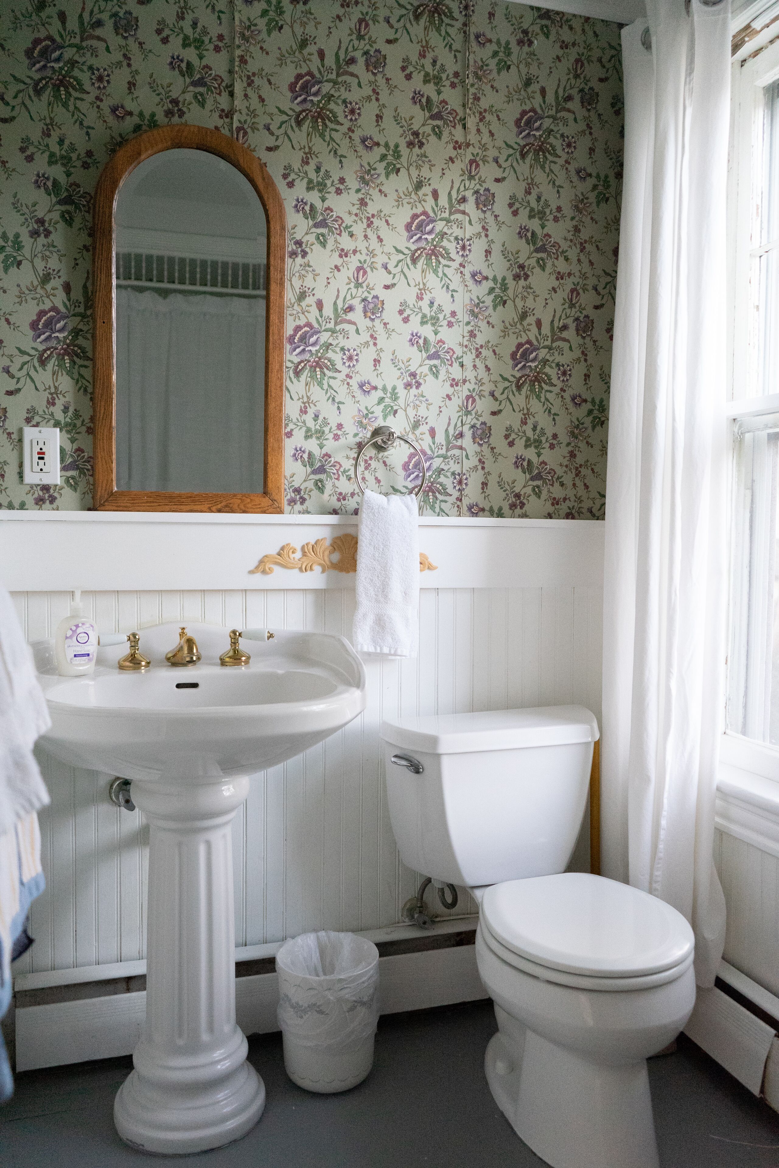A bathroom with a pedestal sink, a toilet, and a mirror.