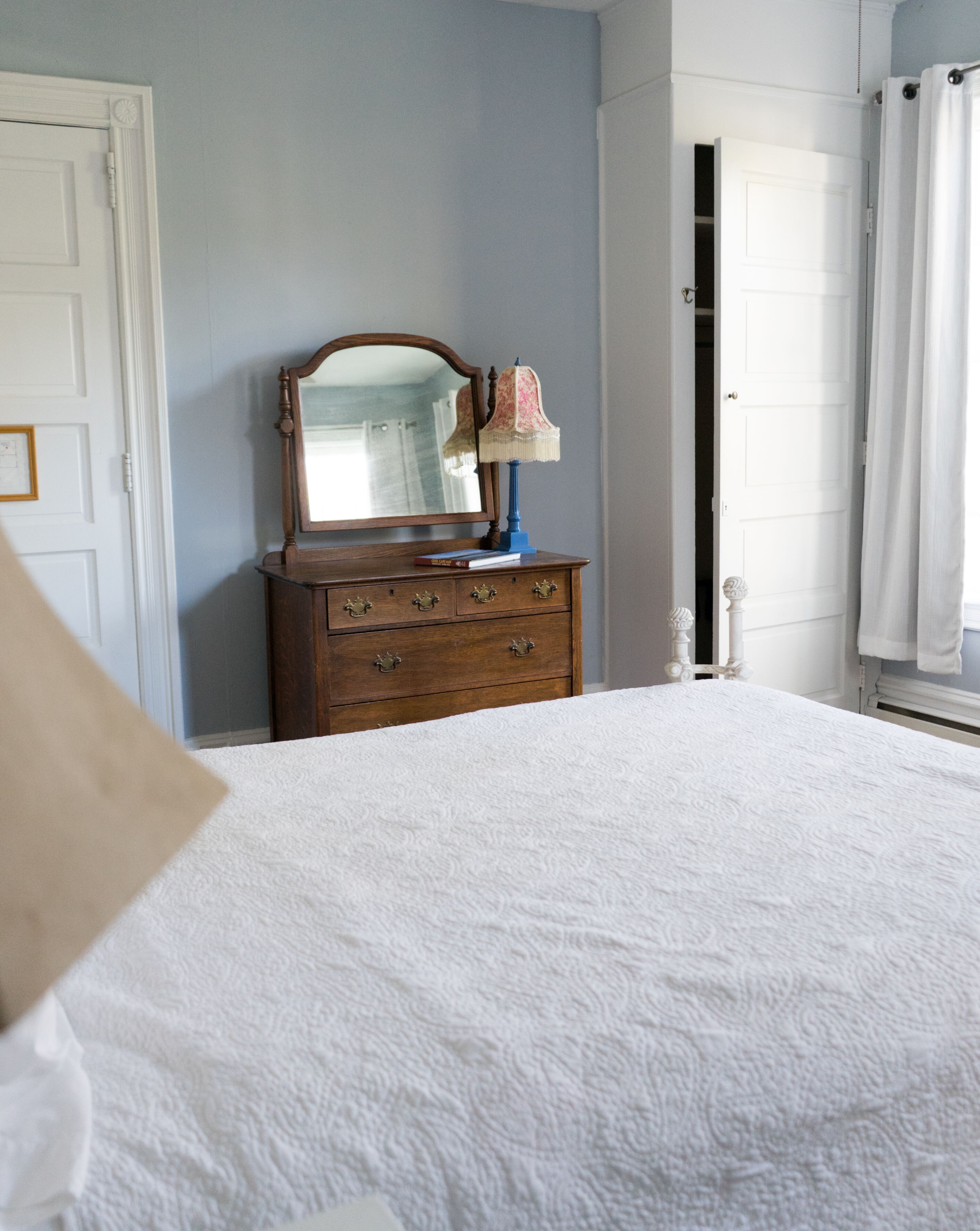 A bedroom with a bed, a dresser with a mirror, and a door.