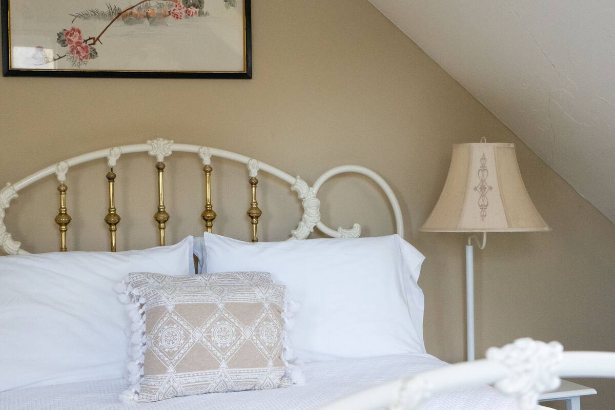 A neatly made bed with a white headboard and a decorative lamp beside it.