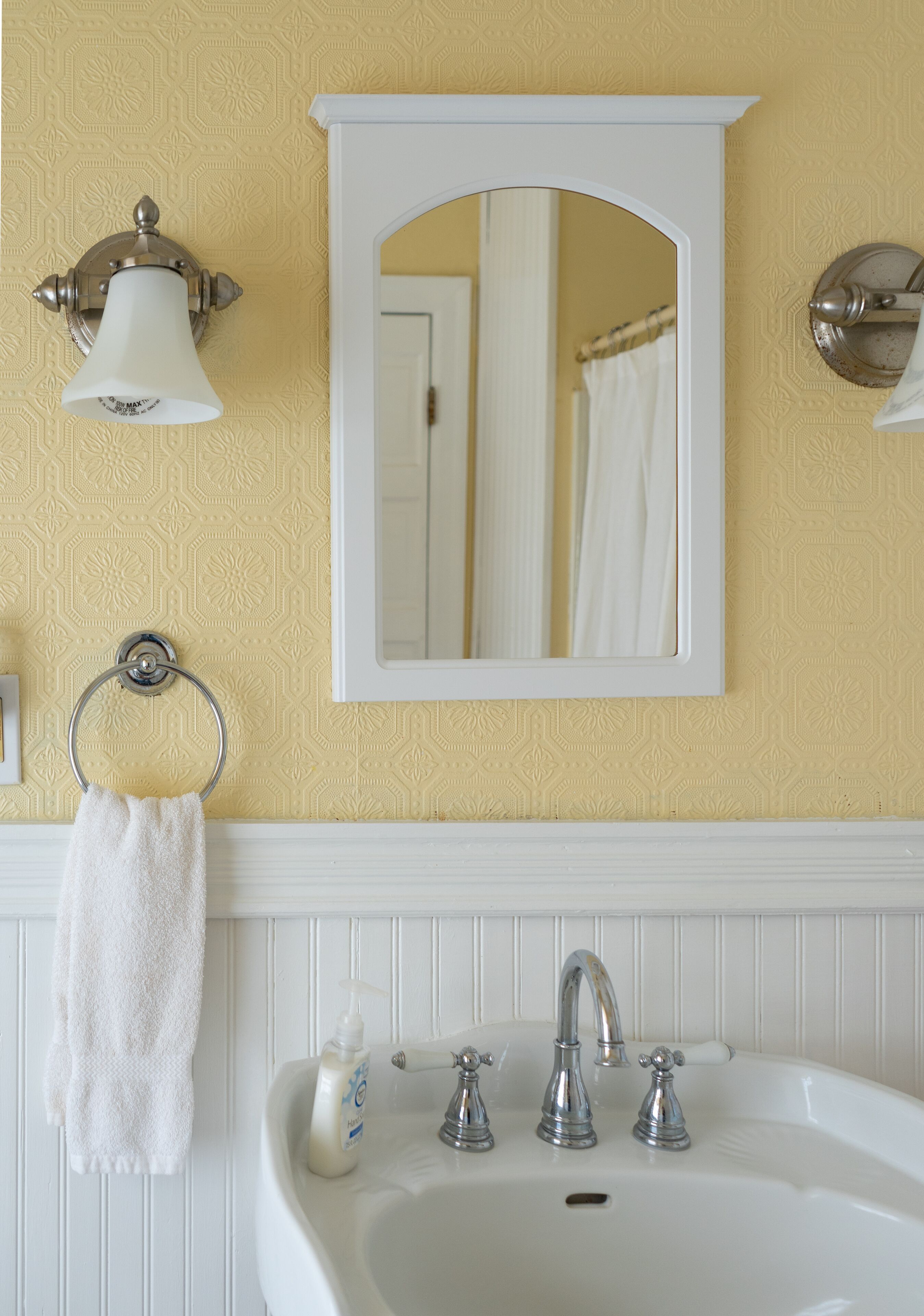 A bathroom with a white sink, two faucets, a mirror, and a towel ring.