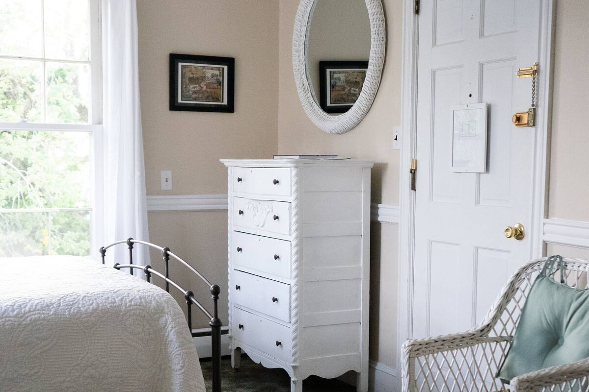 A bedroom with a bed, dresser, chair, and a ceiling fan.