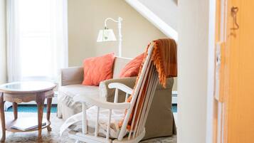 A cozy room with a rocking chair, a small table, and a patterned rug.
