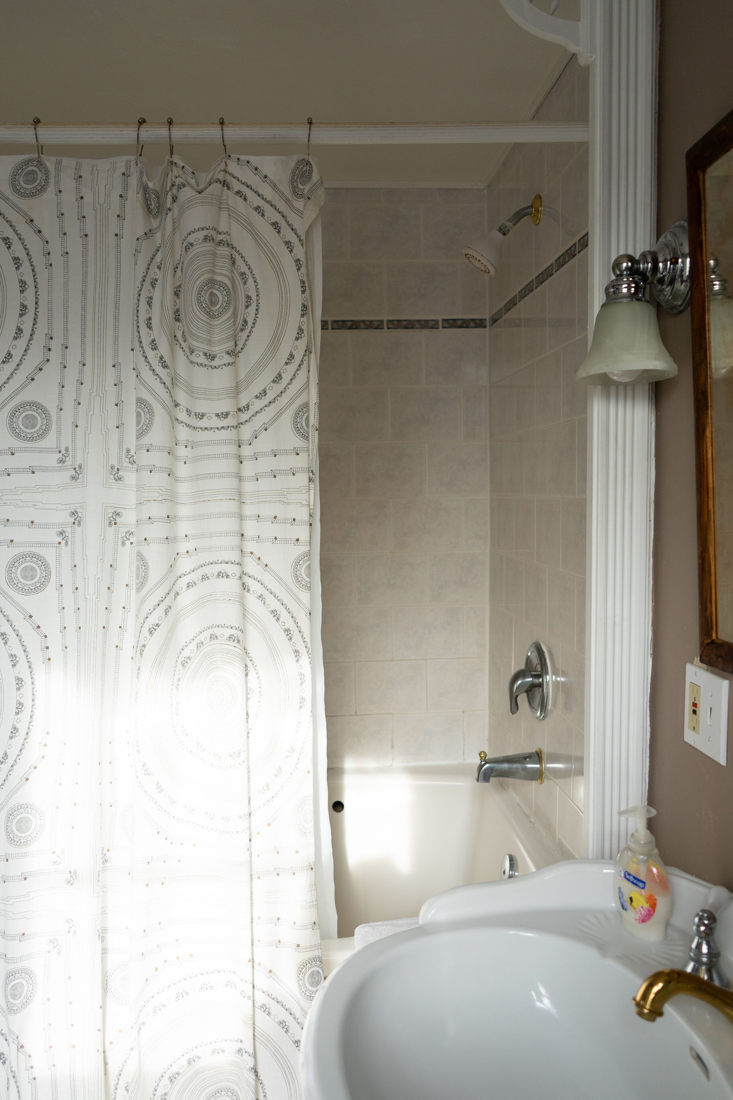 A bathroom with a shower curtain, a bathtub, a sink, and a mirror.