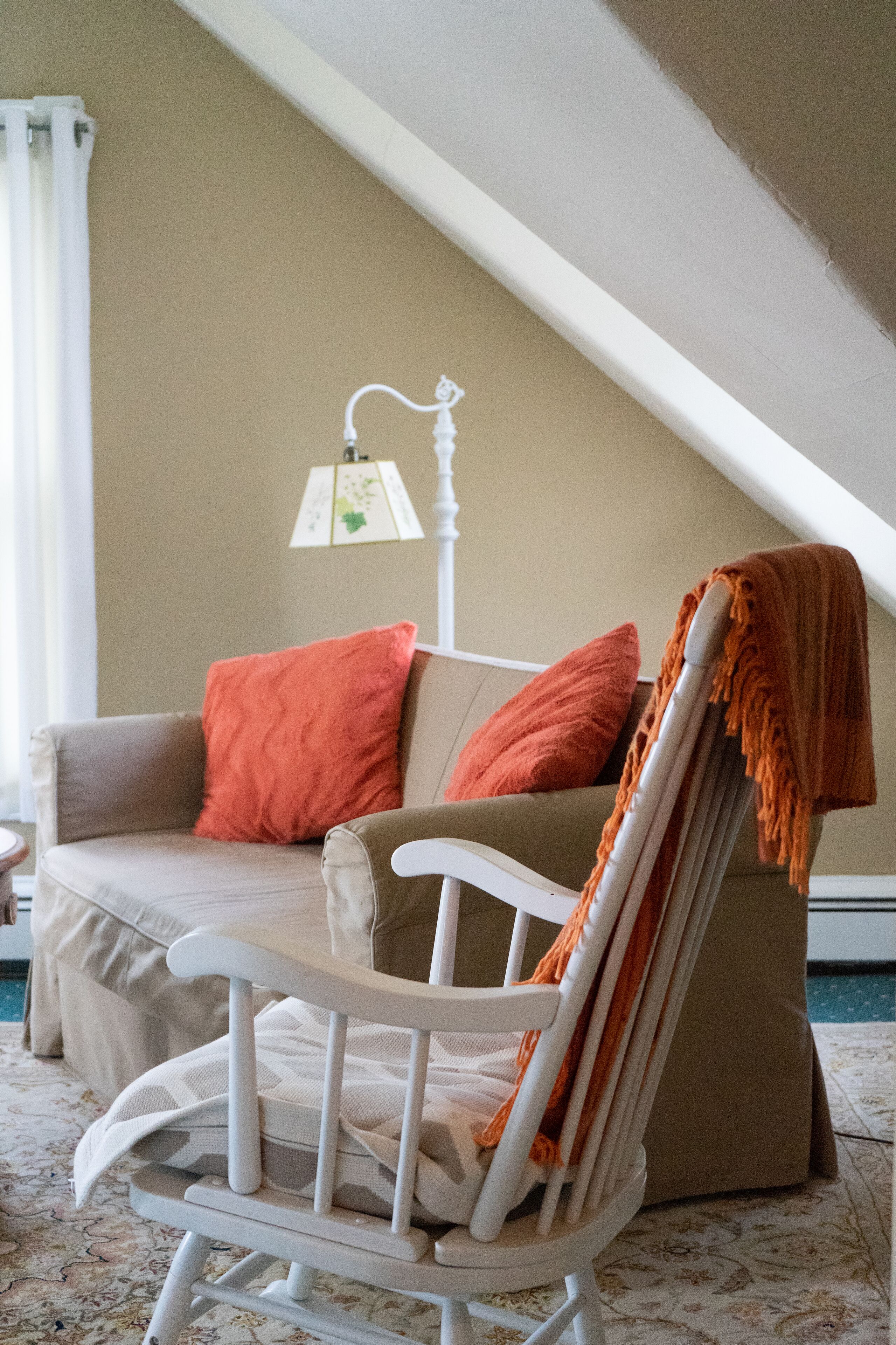 A cozy room with a white chair, a brown sofa, and a lamp.